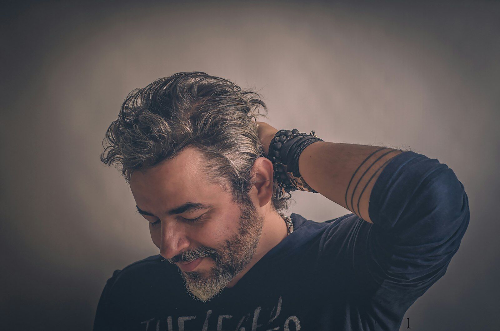 A man with a greying beard checking his hair