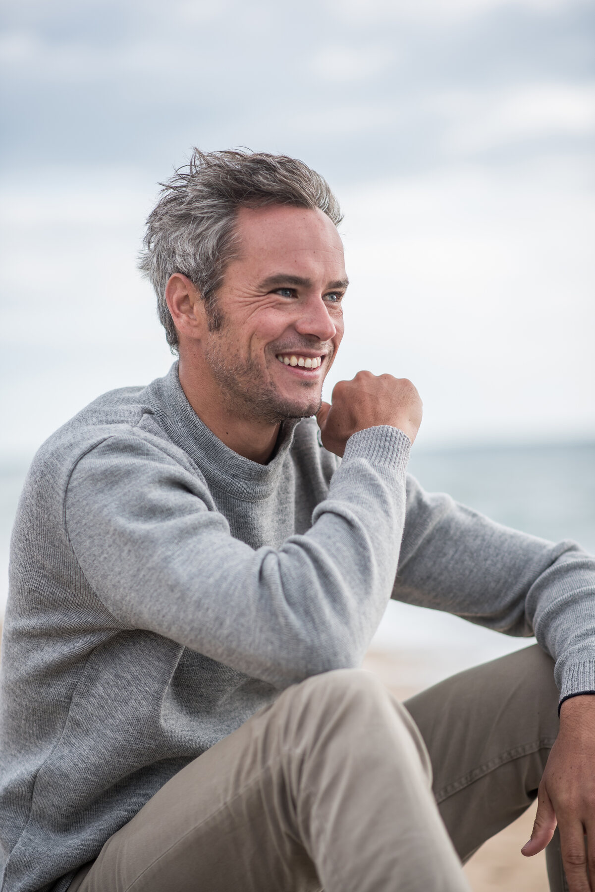 A man with grey hair smiling by the sea