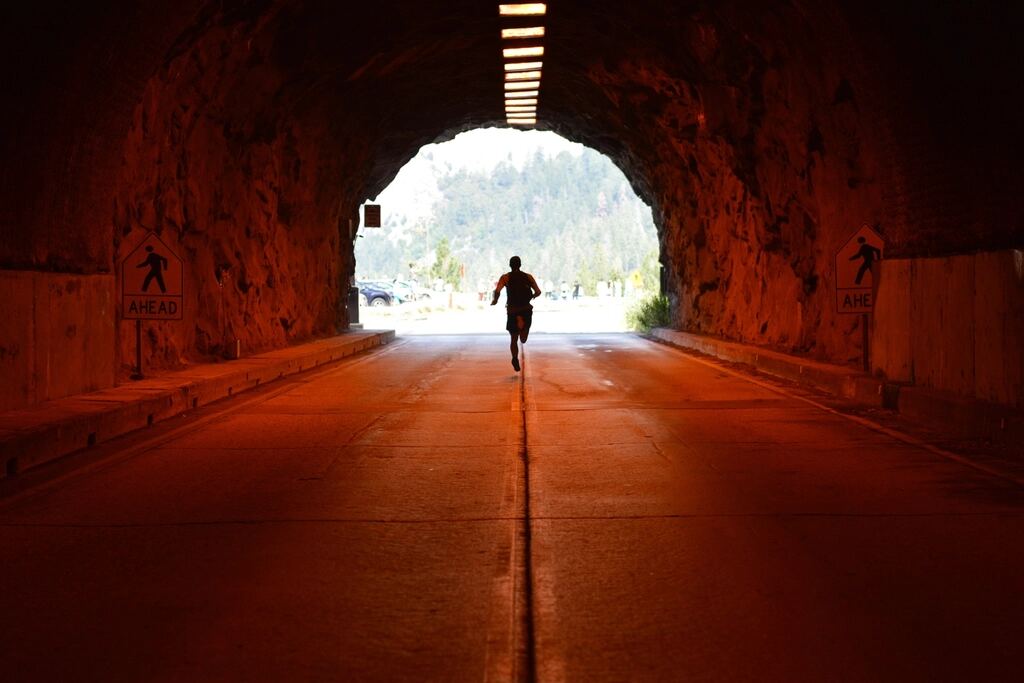 A runner moving through a sunlit tunnel